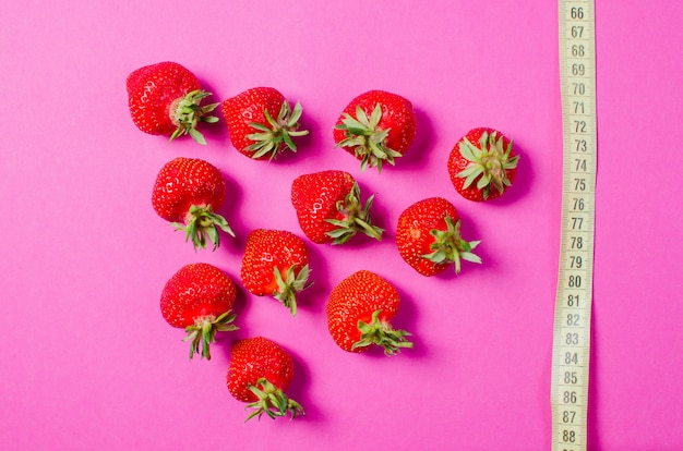 Frische Erdbeeren und Zentimeterband. Das Konzept der richtigen Ernährung. Diätetische Lebensmittel.