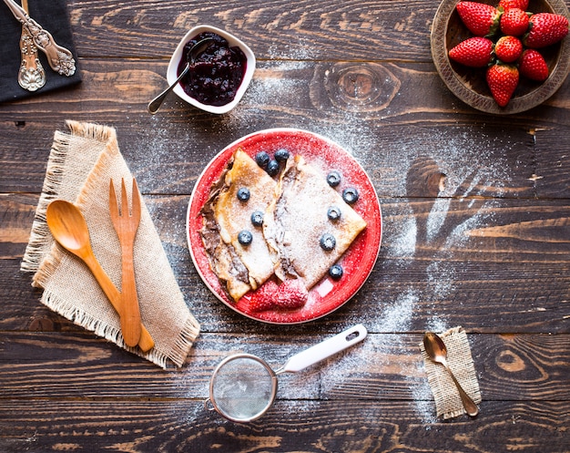 Frische Erdbeerpfannkuchen oder -crepes mit Beeren und Schokolade