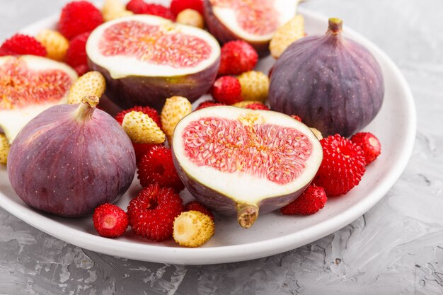 Frische Feigen, Erdbeeren und Himbeeren auf grauem Beton. Seitenansicht