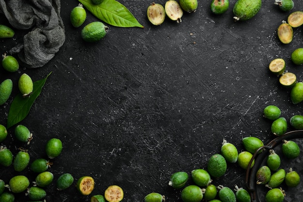 Frische Feijoa-Früchte auf einem Holzbrett Früchte sind reich an Jod Draufsicht auf schwarzem Steinhintergrund