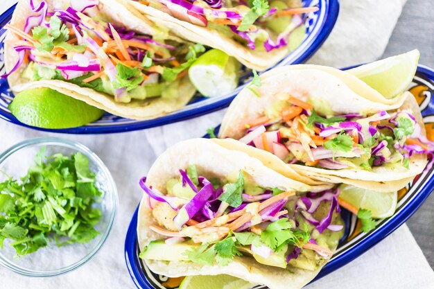 Frische Fisch-Tacos mit Gemüse und Guacamole-Salsa auf weißen Maistortillas.