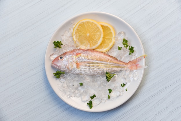 Frische Fische auf Platteneis mit Draufsicht der Zitrone und der Petersilie