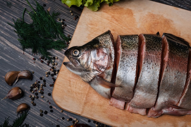 Frische Forellen in Stücke geschnitten auf einem Holzbrett zum Kochen. Roher roter Fisch