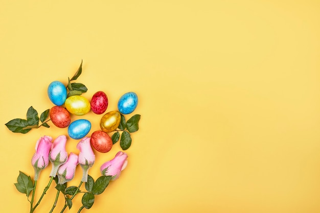 Frische Frühlingsblumen und bunte Ostereier auf gelbem Hintergrund mit Kopienraum. Osterhintergrund mit verzierten festlichen Eiern