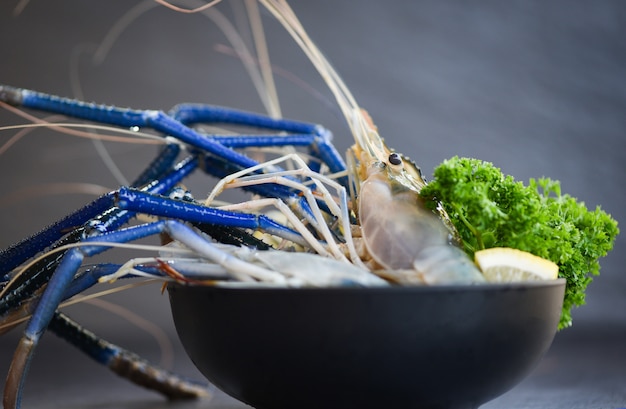 Frische Garnelengarnelen mit Gewürzen zitronengrüne Petersilie zum Kochen von thailändischem Essen von Tom Yum Kung auf dunklem Hintergrund im Fischrestaurant - rohe Garnelen auf Schüssel