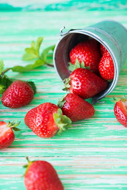 Frische Gartenerdbeeren in einem Eimer auf rustikalem Hintergrund, selektiver Fokus