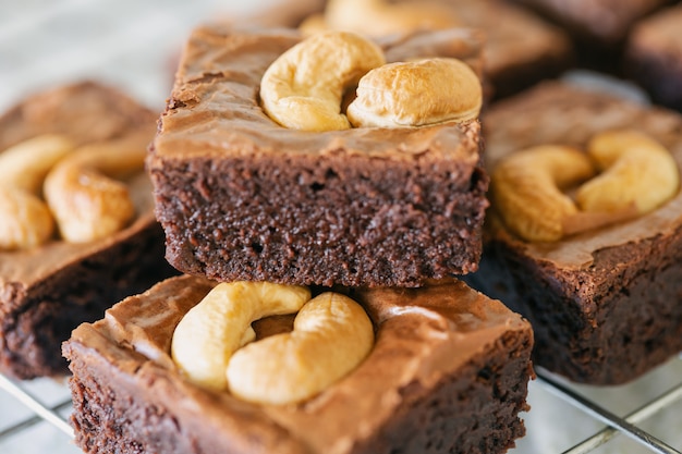 Foto frische gebackene dunkle schokoladenfondantschokoladenkuchen, die mit acajounuss auf gestell im abschluss herauf ansicht übersteigen köstlicher geschmack bitter süß, zäh und fudgy. brownie ist eine art schokoladenkuchen. hausgemachte bäckerei-konzept