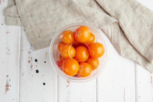 Frische gelbe Kirschtomaten auf weißem Holzhintergrund