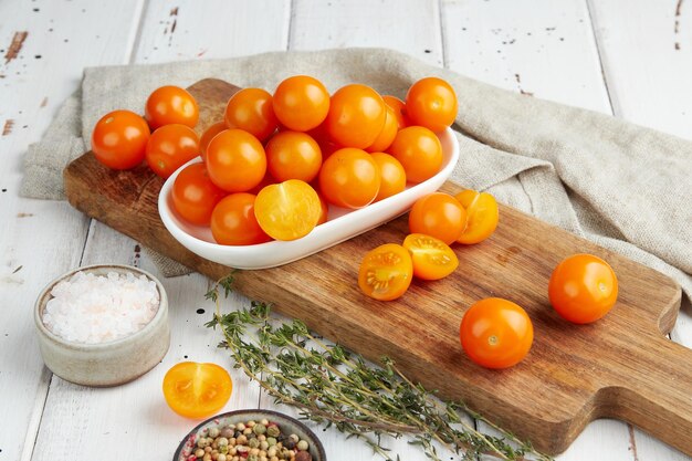 Frische gelbe Kirschtomaten auf weißem Holzhintergrund