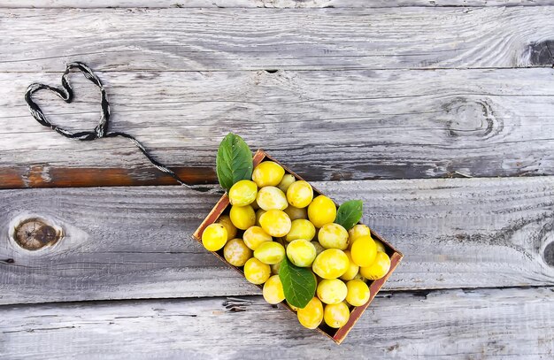 Frische gelbe Pflaumen Reife Früchte in einer Holzkiste auf rauem Bretterhintergrund im Freien