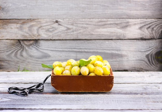 Frische gelbe Pflaumen. Reife Früchte in einer Holzkiste auf rauem Bretterhintergrund