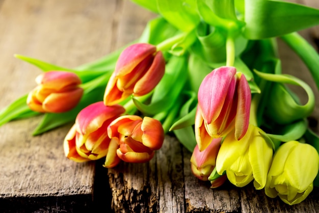 Frische gelbe und rote Tulpen auf alten hölzernen Hintergrundblumen horizontal