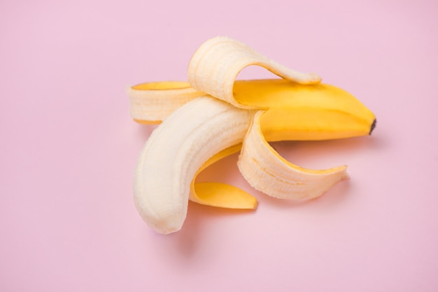 Frische geschälte Banane auf rosa Hintergrund