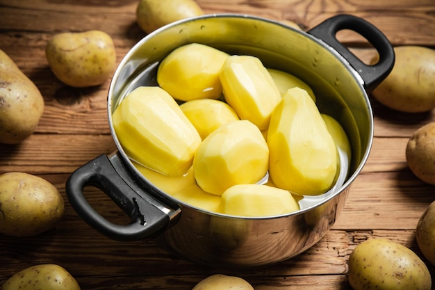 Frische, geschälte Kartoffeln auf einem Holztisch
