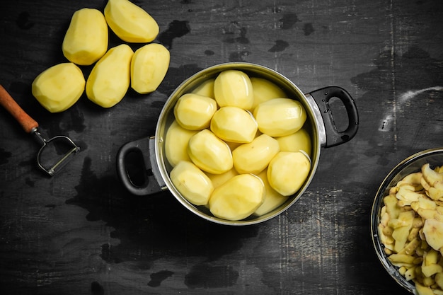 Frische geschälte Kartoffeln auf schwarzem Hintergrund