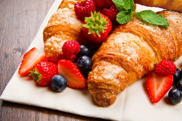 Frische geschmackvolle Hörnchen mit Beeren auf hölzernem Hintergrund