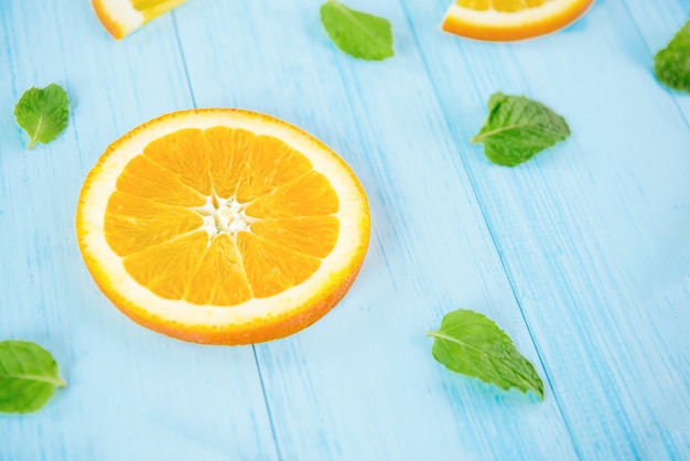 Frische geschnittene Orangen mit Pfeffer verlässt auf hellblauem hölzernem Hintergrund
