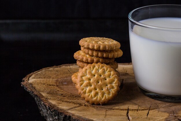 Frische gesunde Milch in Tasse und Stapel Kekse auf schwarzem Hintergrund