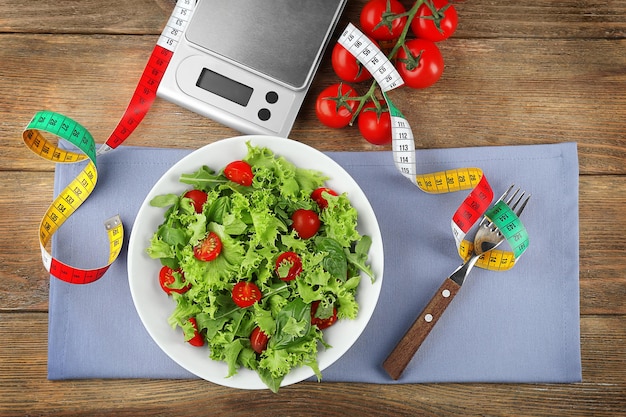 Frische gesunde Salatschuppen und Maßband auf Holzhintergrund