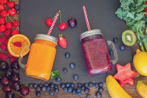 Frische glatte Beeren und gesundes Orangengetränk in Gläsern mit Zutaten