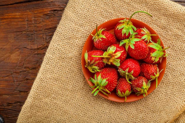Frische große Erdbeeren in einer Tonplatte auf einer Leinenserviette. Horizontales Foto