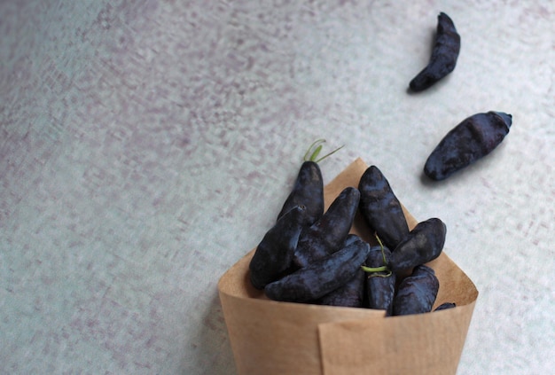 Frische große Geißblattbeere in einem Papierumschlag auf violettem Hintergrund