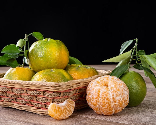 Frische grüne Mandarine Mandarine mit frischen Blättern auf dunklem Holztisch mit schwarzem Hintergrund Erntekonzept.