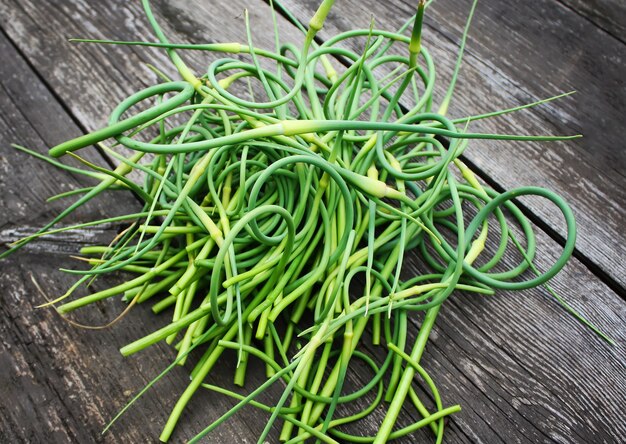 Frische grüne Triebe des Knoblauchs auf einem Holztischhintergrund