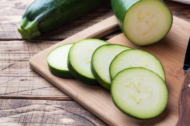 Frische grüne Zucchini auf einem Schneidebrett in Scheiben schneiden.