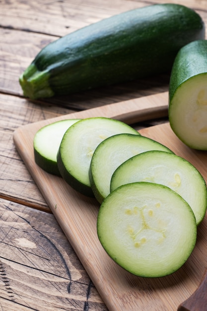 Frische grüne Zucchini auf einem Schneidebrett in Scheiben schneiden.