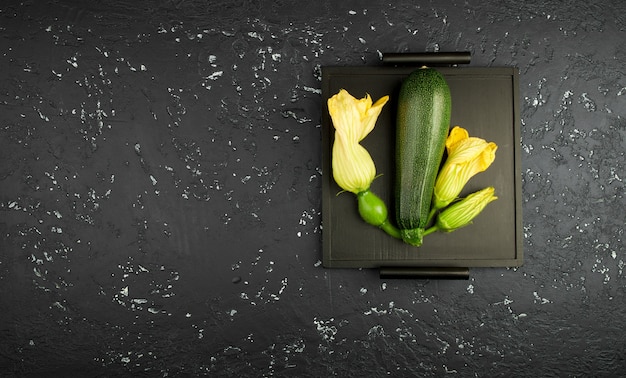 Frische grüne Zucchini auf einer dunklen Tabelle. Der Blick von oben. Kopieren Sie Platz.