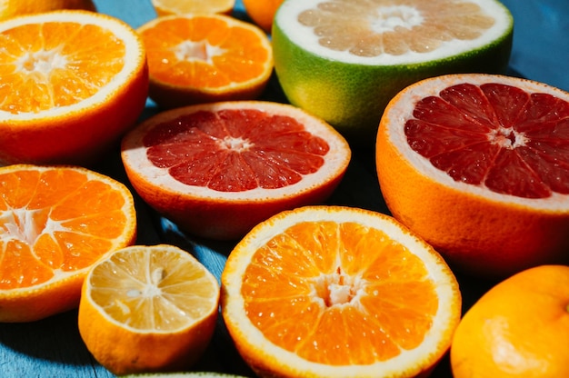 Frische halb geschnittene Orangen-Grapefruit-Mandarinen-Zitrone auf einem blauen Holztisch