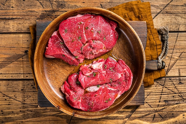 Frische Hammelkotelettsteaks ungekochtes Lammfleisch mit Kräutern Holzhintergrund Ansicht von oben