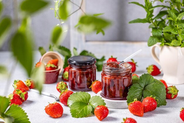 Foto frische hausgemachte erdbeermarmelade in einem glaskrug auf einem hellen hintergrund