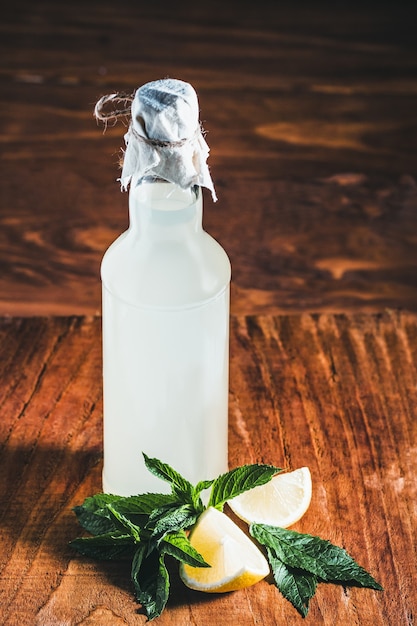 Foto frische hausgemachte flasche limonade, zitronen und minze auf holzhintergrund.