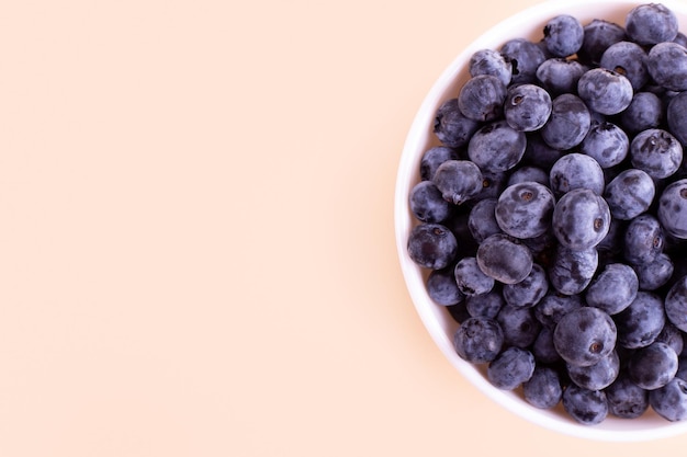 Frische Heidelbeeren auf weißem Teller beige Hintergrund Veganes und vegetarisches Konzept Gesundes Essen im Sommer