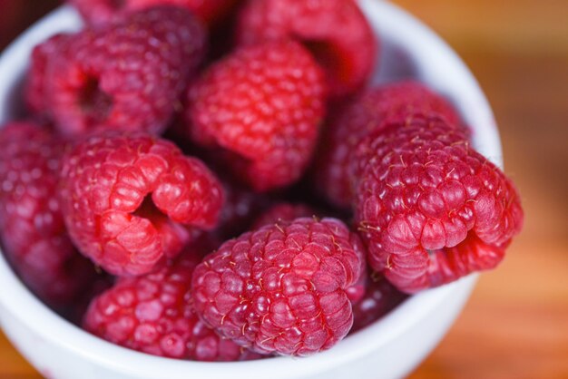 Frische Himbeere auf Schüssel / Abschluss herauf Frucht der roten Himbeeren auf hölzernem Hintergrund