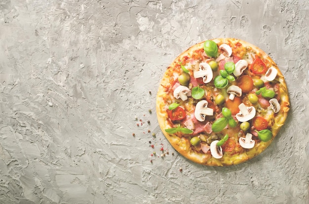 Frische italienische Pizza mit Pilzen, Schinken, Tomaten, Käse, Oliven, Basilikum auf grauem Betonhintergrund. Kopierbereich. Hausgemacht mit Liebe. Schnelle Lieferung. Rezept und Menü-Banner