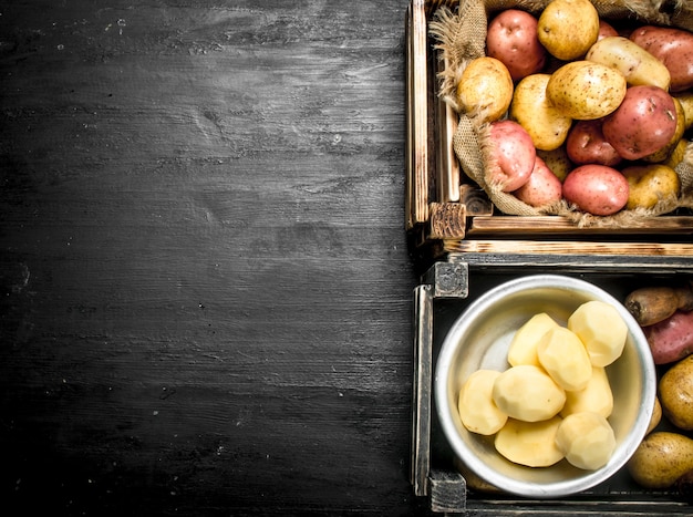 Frische Kartoffeln. Geschälte Kartoffeln in einer Schüssel. Auf der schwarzen Tafel.