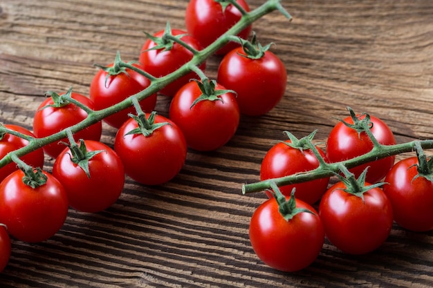 Frische Kirschtomaten auf braunem Hintergrund Bund frischer Kirschtomaten auf einem Holztisch