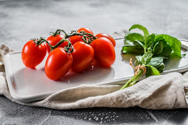 Frische Kirschtomaten auf einem weißen Basilikum. Draufsicht.