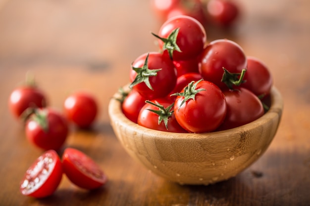 Frische Kirschtomaten in Holzschale auf Holztisch.