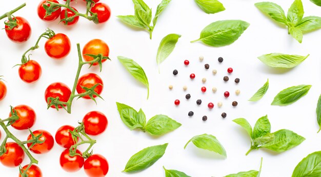 Frische Kirschtomaten mit Basilikumblättern und verschiedenen Pfefferkörnern