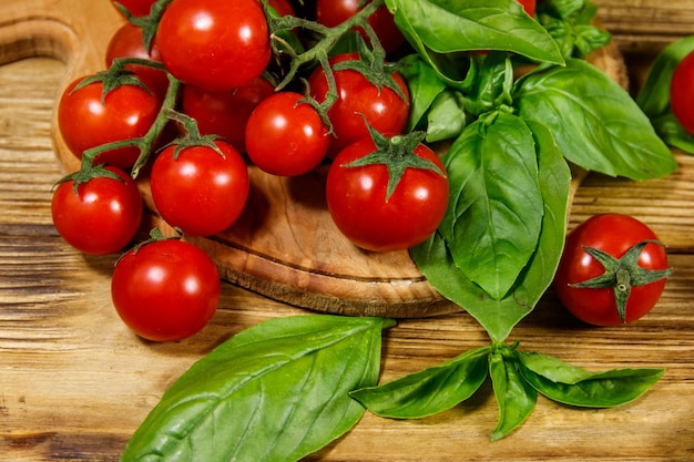 Frische Kirschtomaten mit grünen Basilikumblättern auf einem Holztisch