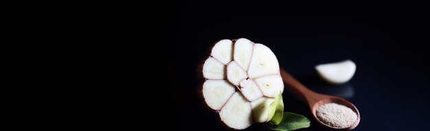 Frische Knoblauchzehe auf schwarzem Hintergrund. Knoblauch ist reich an Vitaminen, nützlicher Frühling, gute Gewürze. Knoblauch auf dunklem Hintergrund geschnitten. Roher geschnittener Knoblauch.