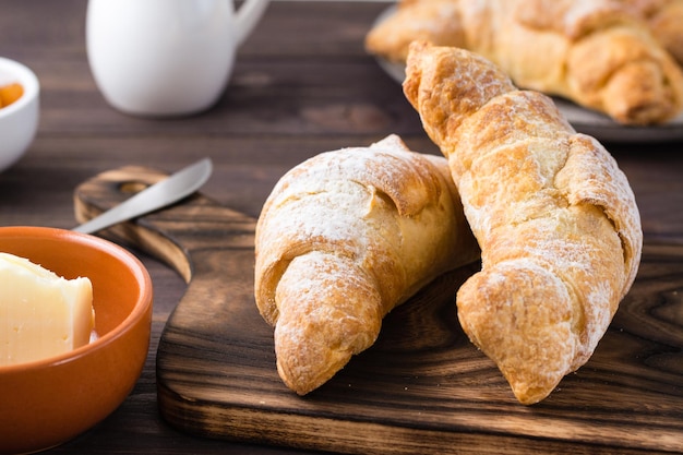 Frische knusprige Croissants auf einem Holzbrett auf dem Tisch. Brunch und Kaffeepause. Nahansicht