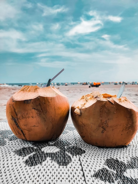 Foto frische kokosnuss, die am strand für zwei personen serviert wird