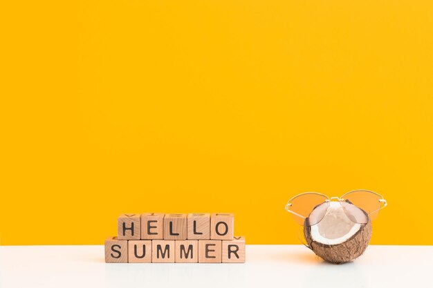 Frische Kokosnuss mit Sonnenbrille auf farbigem Hintergrund Hallo Sommer