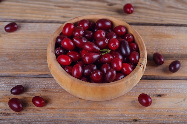 Frische Kornelkirschenbeeren auf einem hölzernen Hintergrund