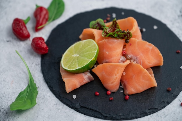 Frische Lachsscheiben mit Paprikagrün und Kalk auf konkretem Hintergrund Beschneidungspfad eingeschlossen